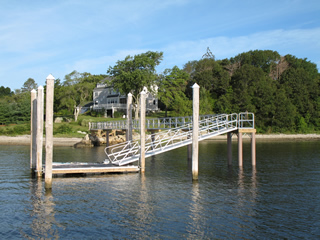 Aluminum gangway and float, held in place by wooden pilings.